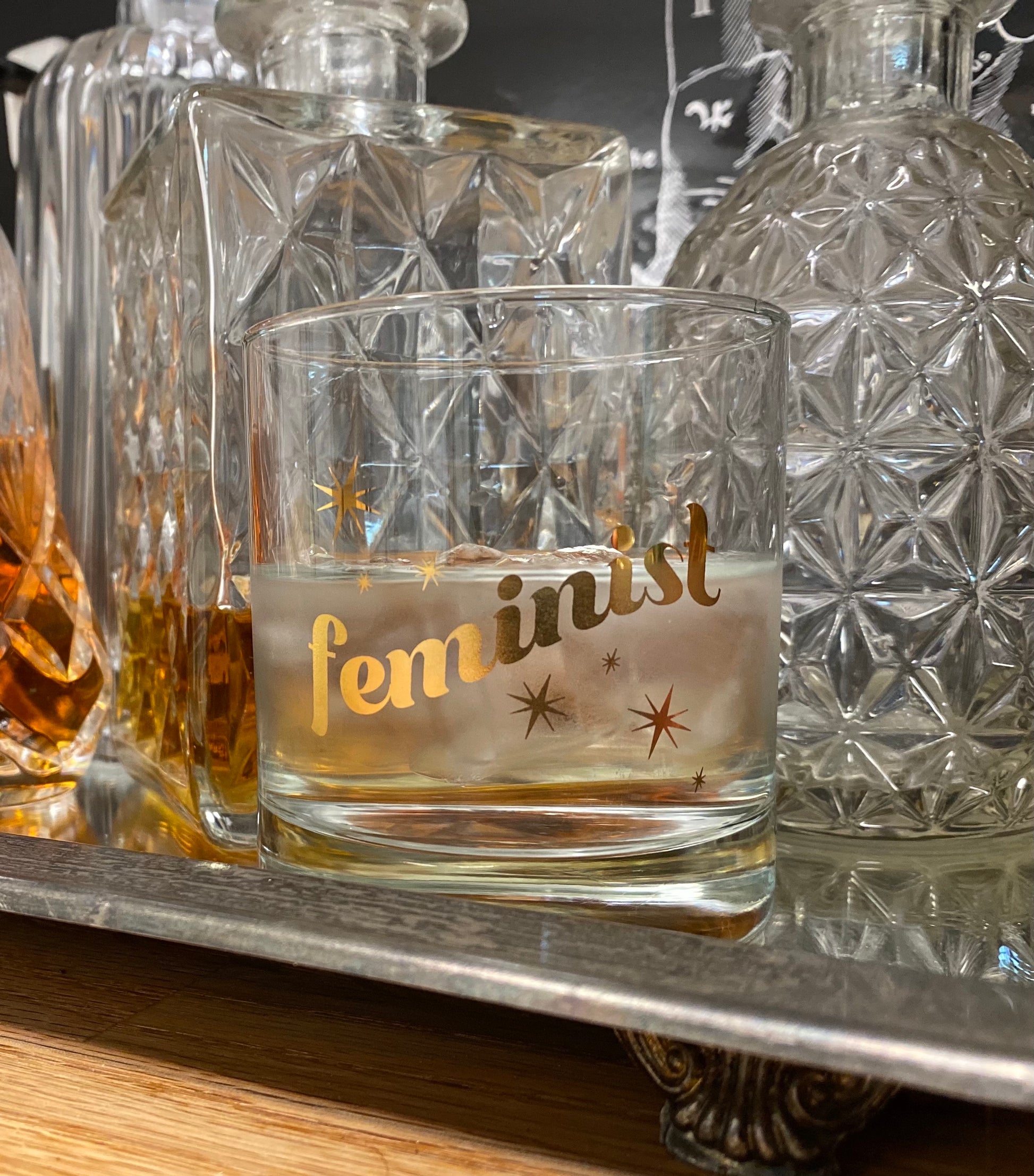 drinking glass that has feminist and stars printed on it in gold
